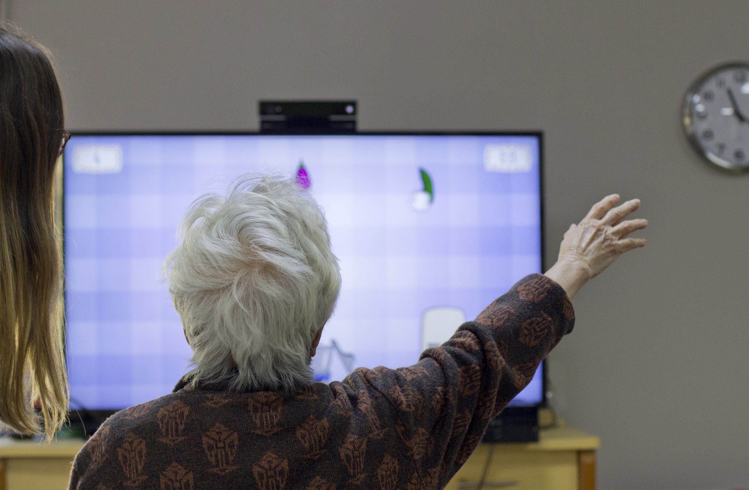 Une résidente d'EHPAD leve le bras droit afin de jouer à Papy Gustatif, un jeu de la plateforme MediMoov